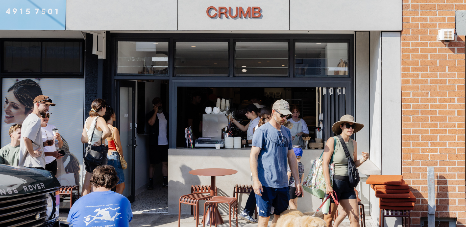 People gather outside a cafe with a shopfront sign that reads "crumb".