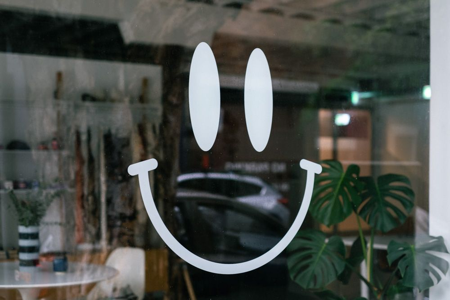 The front window of the Worktones showroom with the decal of the brand's smile icon in focus.